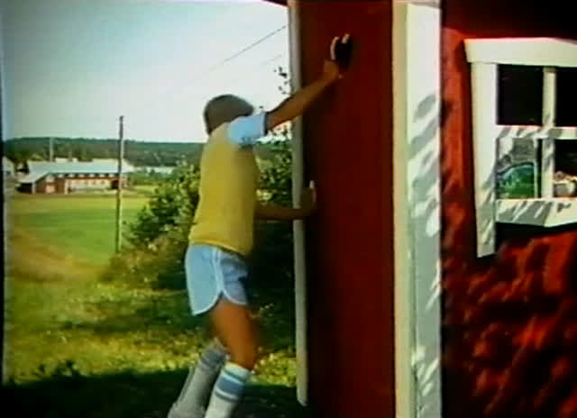 A girl in a yellow top runs along a track towards an open red door.
