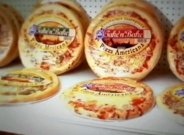Wrapped fresh pizzas on a white shelf, labels reading Take’n’Bake Pizza Americana and Mexicana